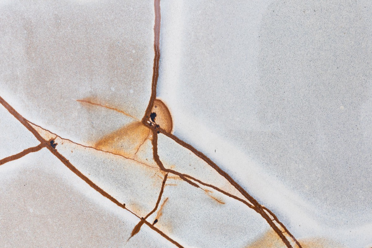 Close-up of a cracked grout line between white tiles in a shower, indicating potential water damage.