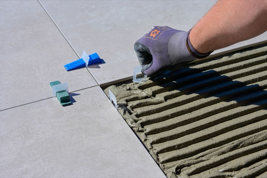 A professional tile setter installing large format porcelain tiles, utilizing a tile leveling system to ensure a perfectly flat and even surface.