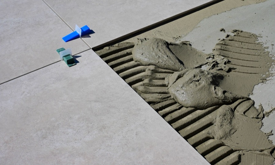 A specialized oscillating tool with a grout removal blade being used to meticulously remove old, damaged grout from between shower tiles.
